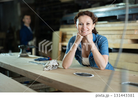 Woman employee of carpentry workshop took time out from work, stands resting 131443381
