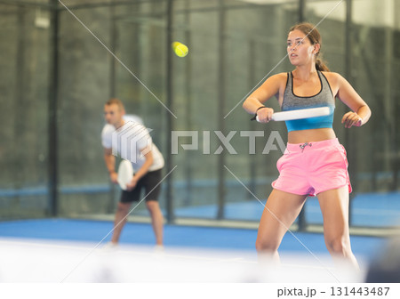 Young woman and man playing doubles tennis Young woman and man playing doubles tennis 131443487
