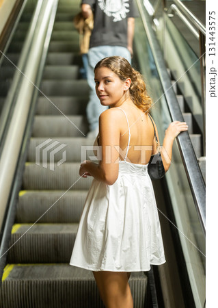Young girl going up on moving staircase Young girl going up on moving staircase 131443575