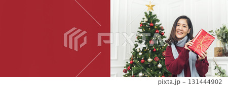 Banner Woman surprise got present gift box on christmas eve. Asian woman holding christmas gift box under xmas tree with smiling face. Happiness Women hands show gift. Merry christmas with copy space 131444902