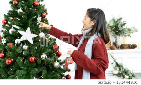 Woman hands decorate Christmas tree red ball, bauble, snow flake. Asian woman decor bauble ball christmas tree in xmas holiday winter seasonal celebration. Close up hands holding silver star decorate Woman hands decorate Christmas tree red ball, bauble, snow flake. Asian woman decor bauble ball christmas tree in xmas holiday winter seasonal celebration. Close up hands holding silver star decorate 131444910