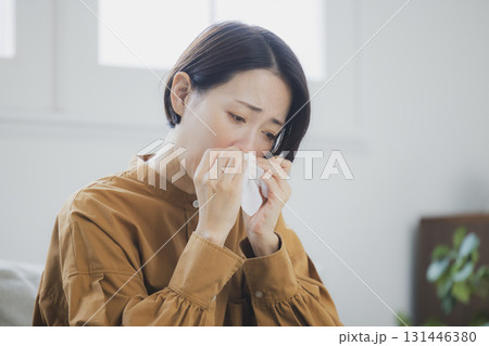風邪をひいて鼻をかむ女性 131446380