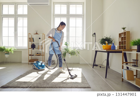 Cleaner, female homeowner tidying up at home, vacuuming carpet, floor in modern living room Cleaner, female homeowner tidying up at home, vacuuming carpet, floor in modern living room 131447901