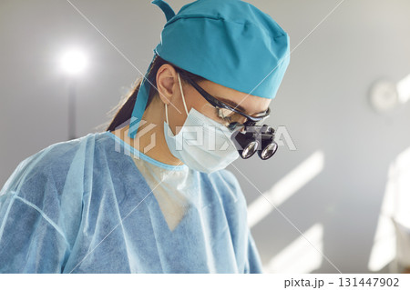 Doctor dentist with dental binocular loupes in blue medical uniform at work in dentistry clinic Doctor dentist with dental binocular loupes in blue medical uniform at work in dentistry clinic 131447902