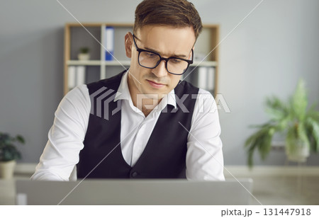 Portrait of confident business man working at the desk on his workplace with laptop in office Portrait of confident business man working at the desk on his workplace with laptop in office 131447918