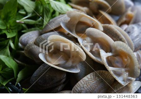 Fresh clams and basil leaves arranged for cooking, showcasing delicious culinary ingredients Fresh clams and basil leaves arranged for cooking, showcasing delicious culinary ingredients 131448363