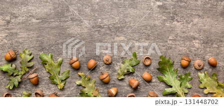 Branch with green oak tree leaves and acorns on colored background, close up top view Branch with green oak tree leaves and acorns on colored background, close up top view 131448702