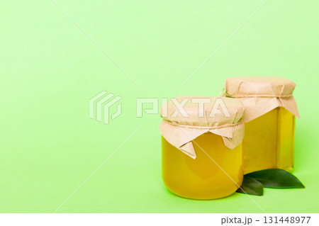 Honey in jar with leaves and honey dipper on colored background top view with copy text Honey in jar with leaves and honey dipper on colored background top view with copy text 131448977