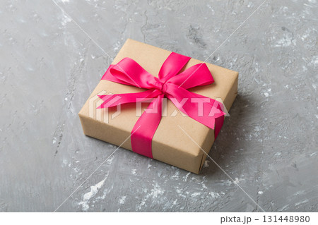 Wrapped christmas or other holiday handmade present in craft paper with colored ribbon. Present box, decoration of gift on table, top view with copy space 131448980