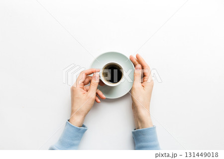 Minimalistic style woman hand holding a cup of coffee on Colored background. Flat lay, top view espresso cup. Empty place for text, copy space. Coffee addiction. Top view, flat lay Minimalistic style woman hand holding a cup of coffee on Colored background. Flat lay, top view espresso cup. Empty place for text, copy space. Coffee addiction. Top view, flat lay 131449018