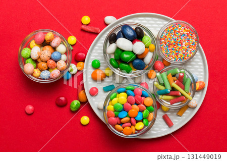 different colored round candy in bowl and jars. Top view of large variety sweets and candies with copy space different colored round candy in bowl and jars. Top view of large variety sweets and candies with copy space 131449019