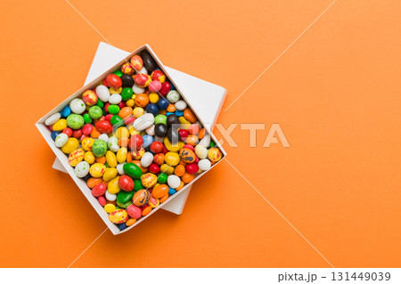 Set of different sweet candy in a paper box with a satin ribbon on a colored background. Holiday concept 131449039