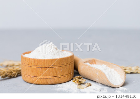Flat lay of Wheat flour in wooden bowl with wheat spikelets on colored background. world wheat crisis Flat lay of Wheat flour in wooden bowl with wheat spikelets on colored background. world wheat crisis 131449110