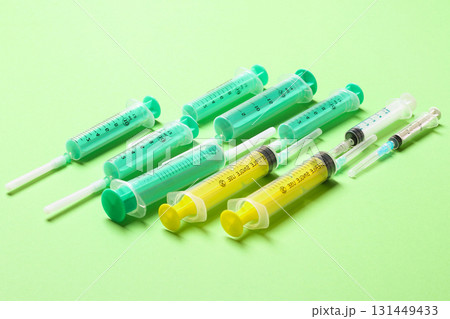 Top view of medical syringes with needles at green background with copy space. Injection treatment concept Top view of medical syringes with needles at green background with copy space. Injection treatment concept 131449433
