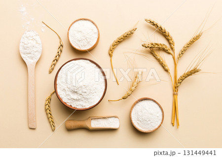 Flat lay of Wheat flour in wooden bowl with wheat spikelets on colored background. world wheat crisis 131449441
