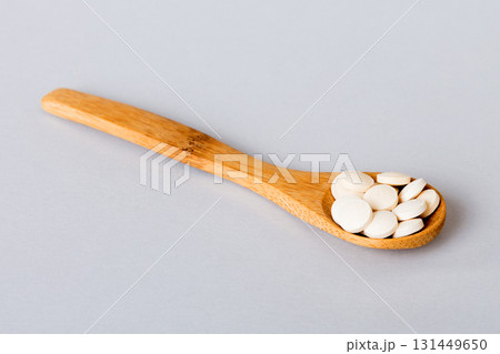 Heap of white pills on colored background. Tablets scattered on a table. Pile of red soft gelatin capsule. Vitamins and dietary supplements concept 131449650
