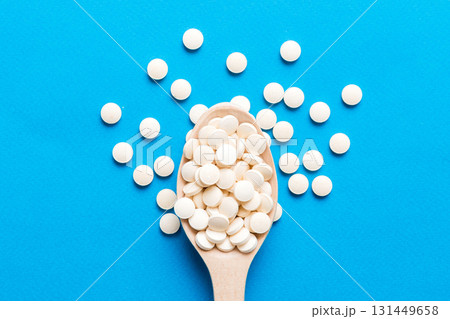 Heap of white pills on colored background. Tablets scattered on a table. Pile of red soft gelatin capsule. Vitamins and dietary supplements concept Heap of white pills on colored background. Tablets scattered on a table. Pile of red soft gelatin capsule. Vitamins and dietary supplements concept 131449658