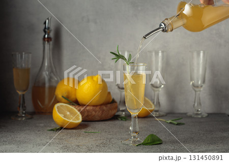 Italian liqueur Limoncello with fresh lemons and rosemary branches on a gray stone table. 131450891
