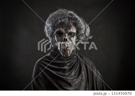 Scary zombie with gray hair over dark background Scary zombie with gray hair over dark background 131450970