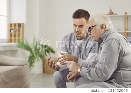 Senior man nursing, health care of elderly people, young male geriatric nurse helping old man with phone 131452046