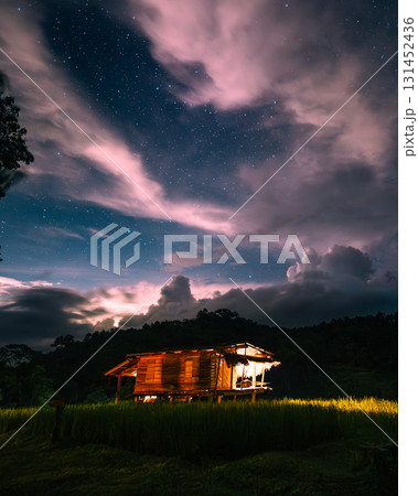 A hut in the middle of a rice field and the belly of a milky way, stars and a night sky with clouds 131452436