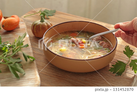 Traditional Italian minestrone soup with vegetables, sausage, and pasta, served in clay bowl on wooden board. Food and healthy lifestyle. Mediterranean cuisine. 131452870