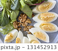 sliced boiled eggs, walnuts, fresh green salad for breakfast 131452913