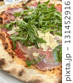 Italian pizza with prosciutto or parma ham, arugula or rocket salad 131452916
