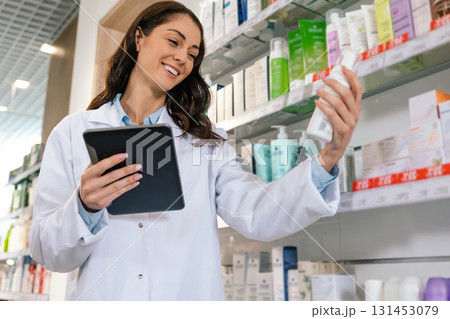 Smiling female pharmacist conducting stock inspection in pharmacy Smiling female pharmacist conducting stock inspection in pharmacy 131453079