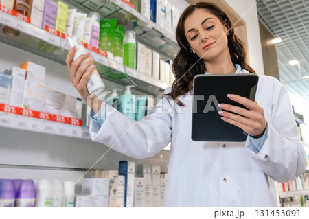 Woman in uniform holding clipboard checking medicine supplies 131453091