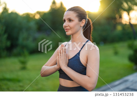 Waist up of a young woman standing with her hands in namaste Waist up of a young woman standing with her hands in namaste 131453238
