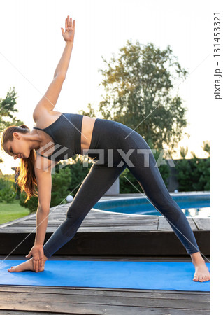 Young yogini standing in a trikonasana pose Young yogini standing in a trikonasana pose 131453321