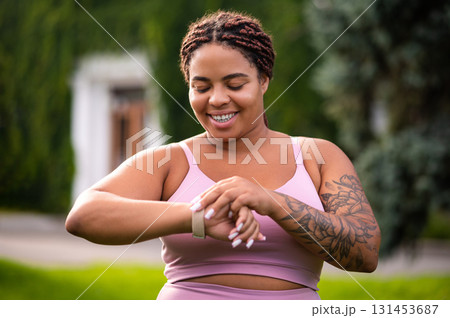 Young woman with a tattoo on her arm looking on her smartwatch 131453687