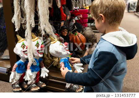 A child chooses a evil clown toy in a store for halloween 131453777