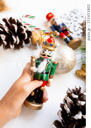 Festive Christmas nutcracker in hand with decorations and pinecones 131453803