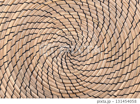 Seagrass place mat, clockwise wound in the shape of a spiral, and sewn with black thread. Natural and organic underlay, made of sedge, a natural Asian seagrass. Background. Close-up, from above. Photo Seagrass place mat, clockwise wound in the shape of a spiral, and sewn with black thread. Natural and organic underlay, made of sedge, a natural Asian seagrass. Background. Close-up, from above. Photo 131454058