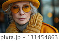 Old fashionable woman, street photo. Lady with grey hair wearing yellow sunglasses and mustard jacket, portrait, outdoors 131454863