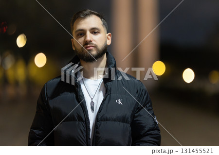 Young man posing in black puffer jacket in urban night Young man posing in black puffer jacket in urban night 131455521