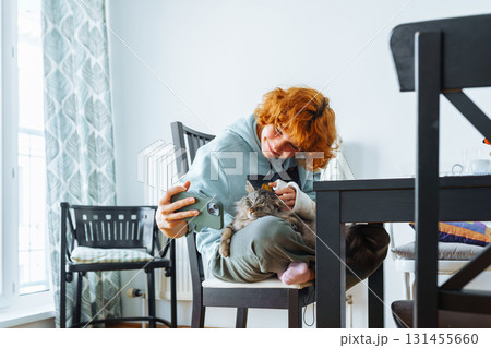 Portrait teenage girl with red hair, cast on arm and domestic cat at home 131455660