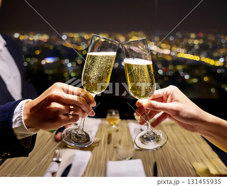 都会の夜景を望む高層レストランで正装した男女がシャンパンで乾杯するロマンチックな夜 131455935