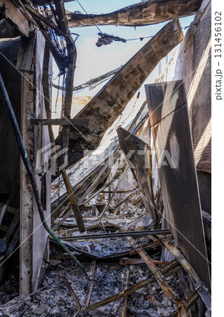 War. The aftermath of Russian airstrikes on a peaceful Ukrainian city. A hospital and a recreation center were destroyed. Fire damaged interior with charred beams, broken roof, and scattered debris. 131456102