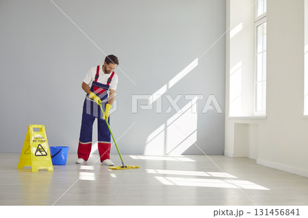 Male Janitor Mops Floors with Diligence 131456841