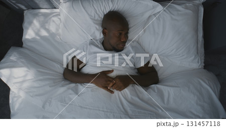 Man Lies in Bed, Stretches, Slowly Wakes Up in Morning Light 131457118