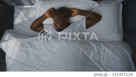 Man Lies in Bed, Stretches, Slowly Wakes Up in Morning Light Man Lies in Bed, Stretches, Slowly Wakes Up in Morning Light 131457119