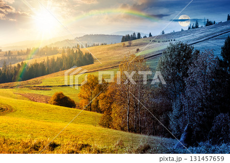 forest on grassy hill on autumn equinox. day and night time change concept. beautiful rural scenery with rolling pasture. mountainous countryside with sun and moon at twilight. warm october weather 131457659