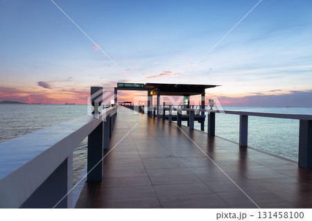 Walkway extending into calm sea at twilight. 131458100