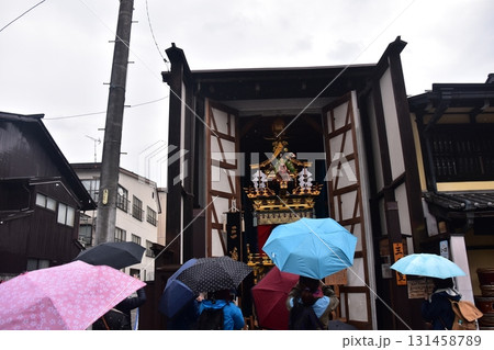日本の岐阜県の高山市　春の高山祭期間中　雨天で蔵に入った豪華な屋台　傘を差して鑑賞する観光客 131458789