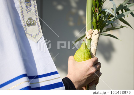 Succot. Jewish man in a Tallit praying while waving the Four Species, Lulav and Etrog Succot. Jewish man in a Tallit praying while waving the Four Species, Lulav and Etrog 131458979