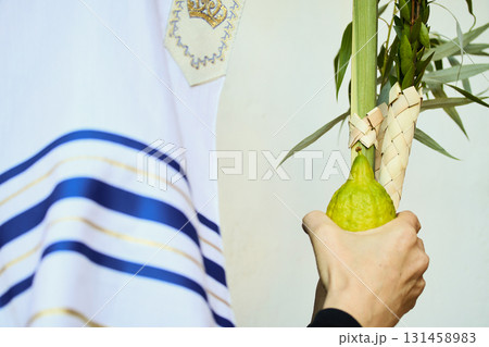 Succot. Jewish man in a Tallit praying while waving the Four Species, Lulav and Etrog 131458983