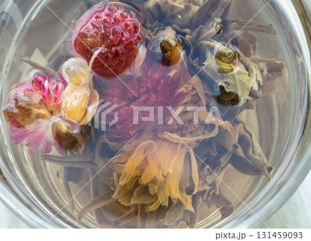 Close-up of Blooming tea (also known as flowering tea or artistic tea). is a type of hand-sewn tea made from dried tea leaves that are wrapped around dried edible flowers. Close-up of Blooming tea (also known as flowering tea or artistic tea). is a type of hand-sewn tea made from dried tea leaves that are wrapped around dried edible flowers. 131459093